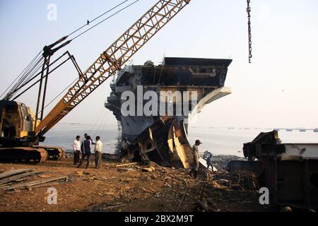 Shipbreaking Yard in Darukhana, Mumbai, India – INS Vikrant dismantling with scrap metal & workers in background Stock Photo