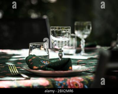 A simple but elegant tablecloth and cutlery laid out on it. Crystal glasses in the sun. Everything is ready for lunch in the garden.France. Stock Photo