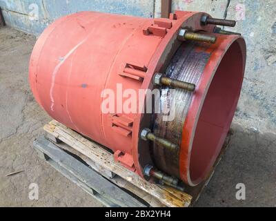 Red gland expansion joint for heating main on concrete floor. Heat and power concept. Stock Photo