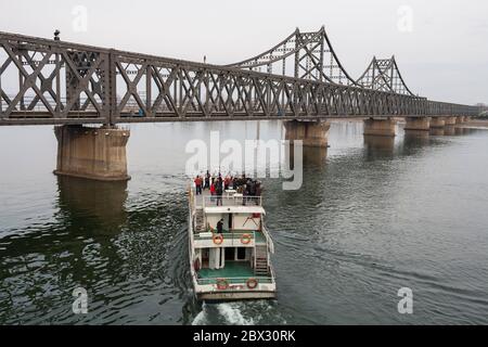 China, Liaoning Province, Dandong City, Sino-Korean Friendship Bridge, tourist boat approaching the North Korean bank of the Yalu River, freight trucks, passenger trains and workers cross this bridge daily Stock Photo