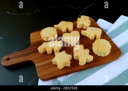 Homemade Delectable Cute Butter Cookies on Wooden Breadboard on Black Background Stock Photo