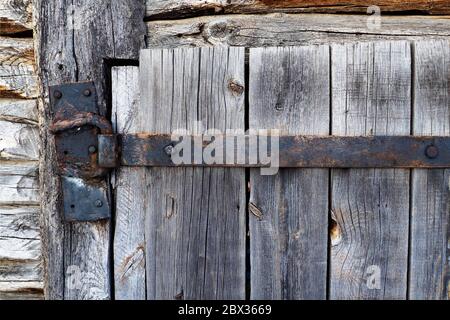 gray rusty aged iron hinge on old wooden door Stock Photo