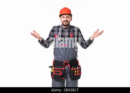Confused bearded builder man wearing overalls and hardhat standing isolated over white background Stock Photo