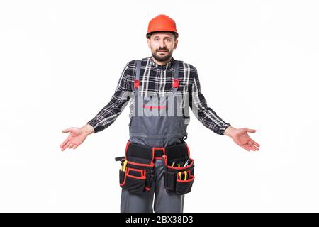 Confused bearded builder man wearing overalls and hardhat standing isolated over white background Stock Photo