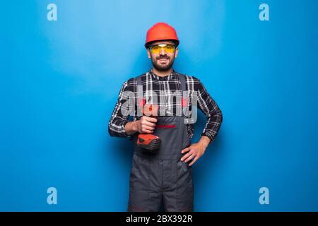 Young male worker or builder with working with electric drill or perforator over blue background Stock Photo
