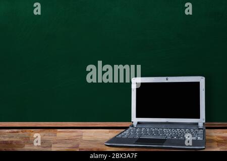 Education back-to-school concept in classroom setting showing laptop computer on table with copy space on chalkboard. Stock Photo