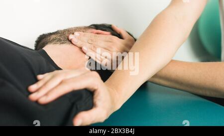 Physiotherapist doing massage and stretching with person on a therapy table. Stock Photo