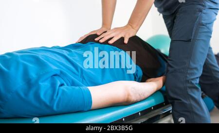 Physiotherapist exercising with disabled person on a therapy table. Stock Photo