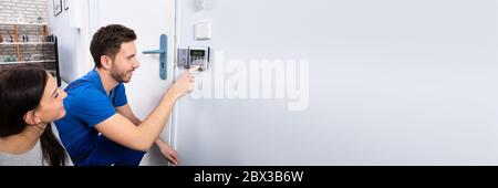 Alarm System Security Installation At Home. Technician Installing Near Door Stock Photo