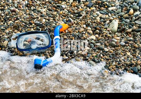 Blue snorkel and mask for diving on the pebble beach Stock Photo