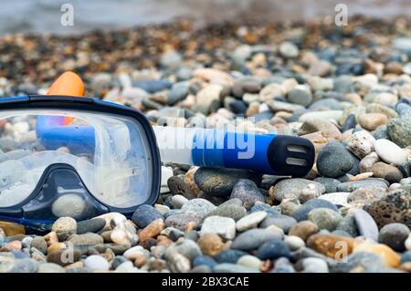 Blue snorkel and mask for diving on the pebble beach Stock Photo