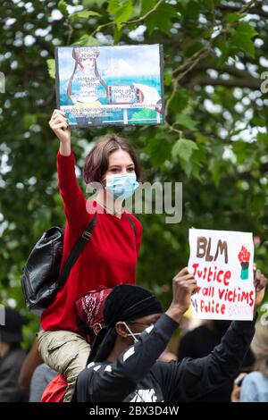 A young white girl riding piggyback and holding up a sign at the Black Lives Matters protest in Hyde Park, London, 3 June 2020 Stock Photo