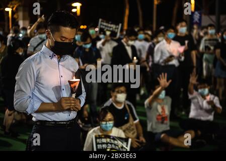 A man bows his head while holding a candle during the anniversary rally.Thousands of Hong Kong residents attended a rally commemorating the 31st anniversary of the Tiananmen Square Massacre. Rally attendees chanted slogans, lit candles and held a moment of silence in remembrance of the day. Stock Photo