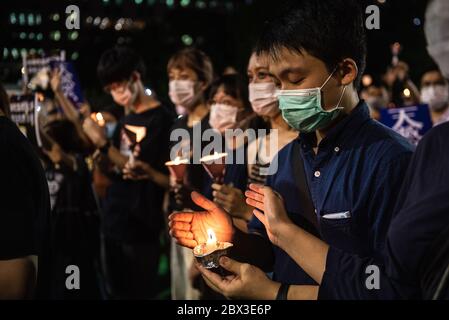 Participants shield their candles from the wind during the anniversary rally.Thousands of Hong Kong residents attended a rally commemorating the 31st anniversary of the Tiananmen Square Massacre. Rally attendees chanted slogans, lit candles and held a moment of silence in remembrance of the day. Stock Photo