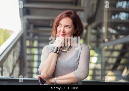 Closeup headshot portrait charming smiling joyful happy mature business woman looking upwards daydreaming nice future thinking isolated outside backgr Stock Photo