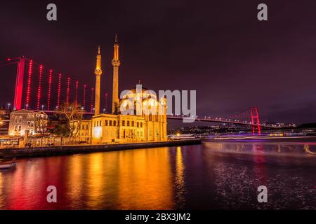 Ortakoy Camii mosque with two minarets backlighted shot at blue hour with new bridge as background at Istanbul, Turkey. Stock Photo