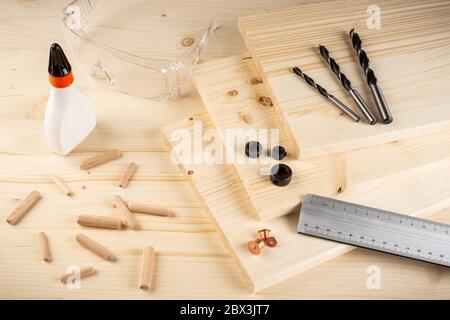 wooden dowel joint pins drill glue wood planks safety glasses and tools on spruce background. Carpenter industry funiture making concept. Stock Photo