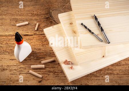 wooden dowel joint pins drill glue wood planks and tools on rustic oak background. Carpenter industry funiture making concept. Stock Photo