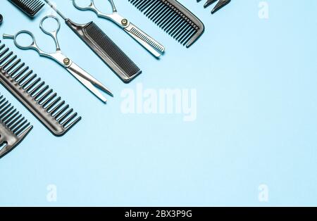 Black combs and combs with scissors on blue background. Copy space for text Stock Photo