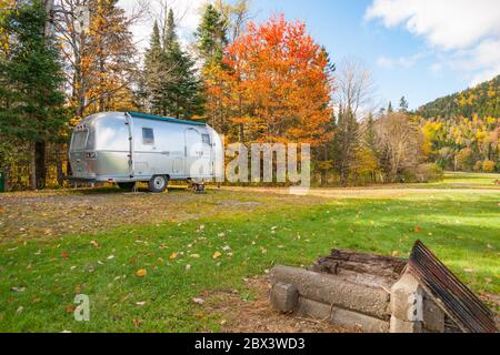 Maine USA -October 6 2014; American iconic travel trailer parked in great outdoors in shady spot under autumn color trees.. Stock Photo