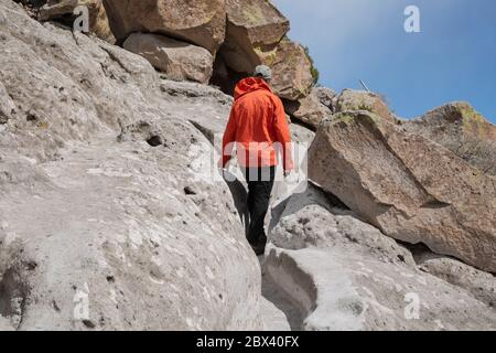 NM00500-00...NEW MEXICO - Hiker walking the narrow trail worn in to the soft stone by the Ancestral Puebloans at the Tsankawi Unit of Bandelier NM. Stock Photo