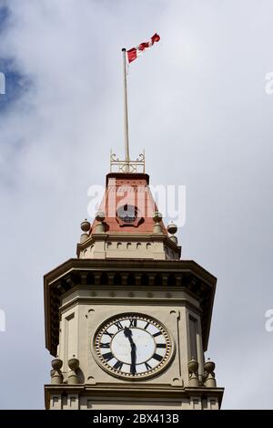 A view of the Canadian flag flying over the clock tower on the old city hall building on Douglas Street in downtown Victoria, British Coumbia, Canada Stock Photo