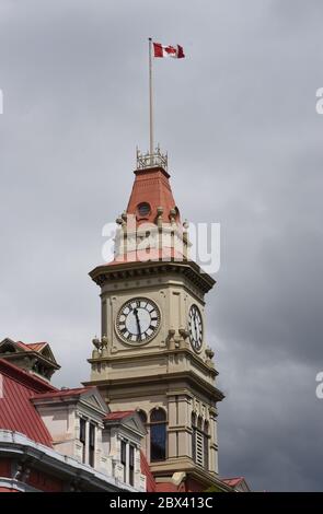 A view of the Canadian flag flying over the clock tower on the old city hall building on Douglas Street in downtown Victoria, British Coumbia, Canada Stock Photo