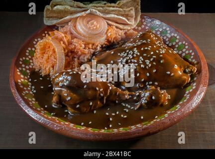 Traditional Mexican food, Mole with sesame, Mexican tomato rice, and corn tortillas on a clay or mud plate. Stock Photo