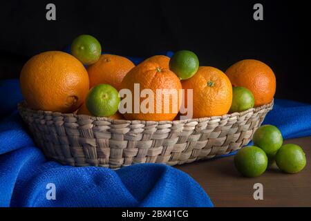 still life, low key light, oranges and lemons in a Mexican basket on a blue table cloth Stock Photo