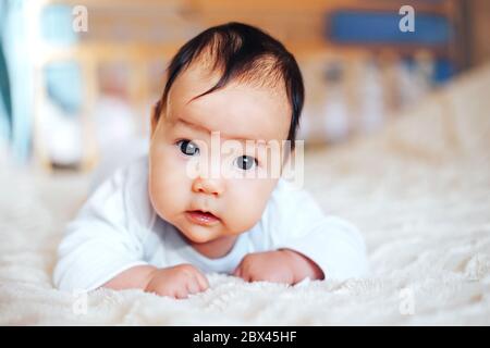 Baby girl on her stomach. Looking up with surprised expression. Stock Photo