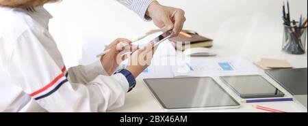 Side view of UI developer team consulting on their project with smartphone while working in meeting room Stock Photo