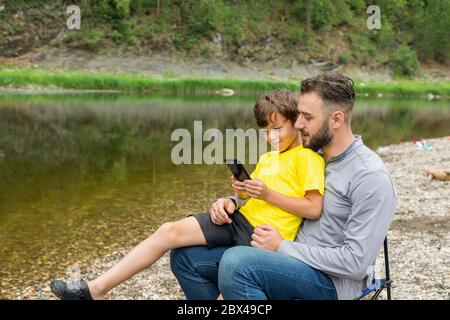 father and son using smartphone. Concept of family moment using mobile technology. Stock Photo