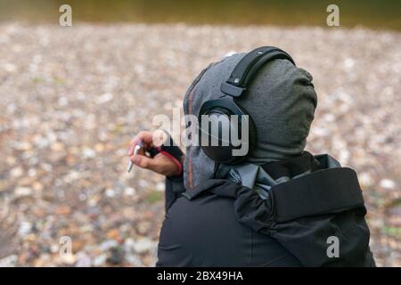 young handsome hipster man relaxing smoking cigarette and enjoy listening to music in beach. freedom concept. Copy space. Stock Photo
