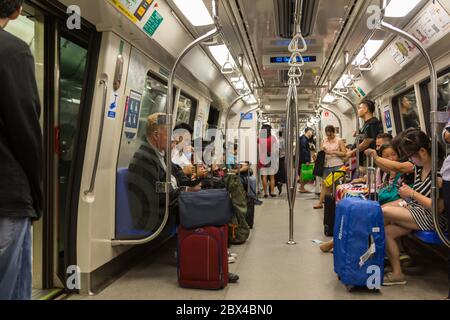 SINGAPORE - JULY 07, 2017: Unidentified Passengers in a crowded Mass Rapid Transit (MRT) subway train arriving at the City Hall station in the busines Stock Photo