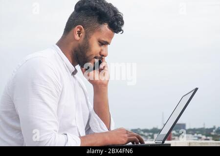 young man using laptop and smart phone together Stock Photo