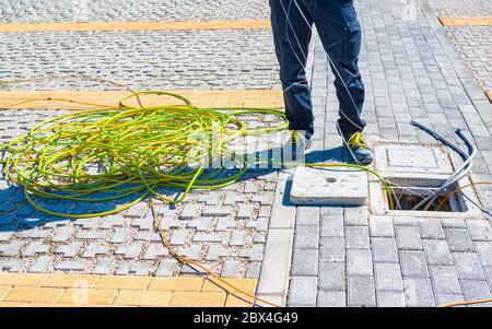 Worker inserts a yellow and green electric cable on the ground in an inspection line of the power line Stock Photo