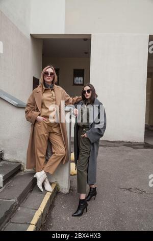 Outdoor fashion portrait of two young beautiful women wearing trendy stylish clothes,laughing and looking away, posing in street of european city Stock Photo