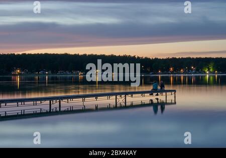 01 June 2020, Brandenburg, Eberswalde: A man and a woman sit on a jetty at Werbellinsee in the evening. In the year of the Corona crisis, domestic holidays become interesting again. Photo: Annette Riedl/dpa-Zentralbild/ZB Stock Photo