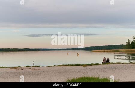 01 June 2020, Brandenburg, Eberswalde: A man and a woman sit on the shore of Werbellinsee in the evening. In the year of the Corona crisis, domestic holidays are becoming interesting again. Photo: Annette Riedl/dpa-Zentralbild/ZB Stock Photo