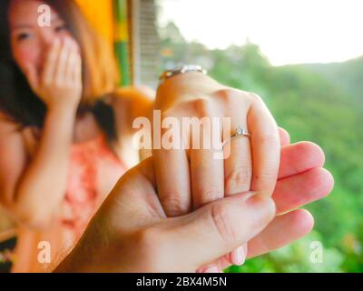 close up couple hands man holding happy fiance hand with diamond engagement ring on her finger after wedding proposal at tropical beautiful and romant Stock Photo