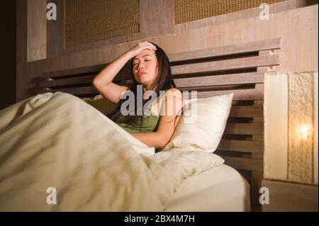 lifestyle night portrait of young beautiful depressed and sad Asian Chinese woman having insomnia lying in bed sleepless suffering anxiety stress and Stock Photo