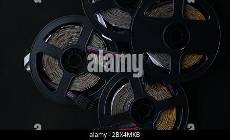 Coils of rgb led strip on a black table. Led strip for creative lighting collected in a black coil, tools for lighting and light effects. Stock Photo