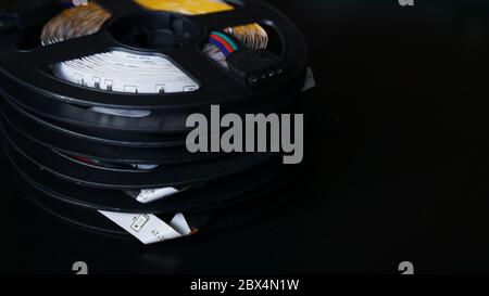 Coils of rgb led strip on a black table. Led strip for creative lighting collected in a black coil, tools for lighting and light effects. Stock Photo