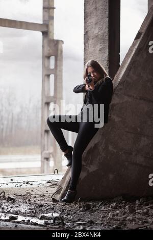 Woman with a machine gun in an abandoned building Stock Photo