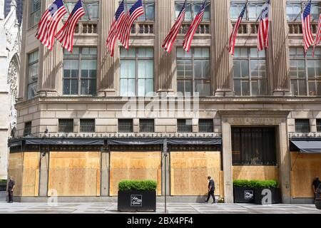 New York, NY. 3rd June 2020. The flagship Saks Fifth Avenue department store with boarded up windows, barbed wire, and American flags in response to a recent spate of large scale, organized burglaries/looting in various parts of the city. The barbed wire and private security appears to send an almost dystopian, and tone deaf message to the citizens of New York that all hope is lost.  On the flip side, it is an immensely Instagrammable photo op. The department store has been closed during the COVID-19 coronavirus pandemic. Stock Photo