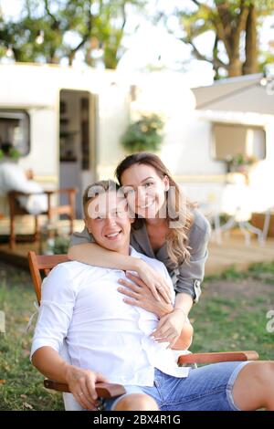 Husband and caucasian wife sitting in chair near house on wheels. Stock Photo
