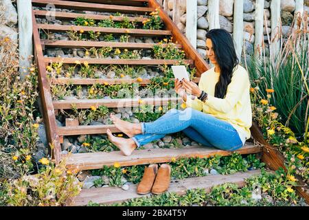 Woman relaxing and reading ebook in a garden Stock Photo