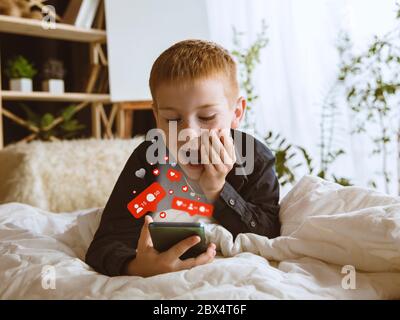 Boy connecting and sharing social media with smartphone and headphones. Modern UI icons, communication, devices. Concept of modern technologies, networking, gadgets, daily online life. Design. Stock Photo