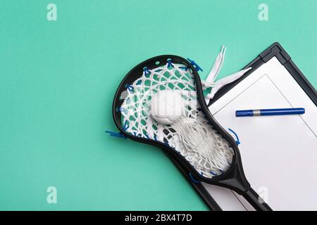 Lacrosse stick, ball and tactical board with marker on green background. Sport coach concept Stock Photo