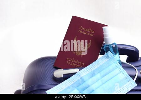 Thai passport on suitcase with medical mask and hand sanitizer spray. Lifestyle and travel concept in New Normal after Covid-19 / Coronavirus pandemic. Stock Photo
